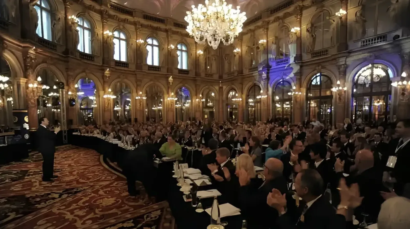 A large formal dinner gathering in an ornate ballroom